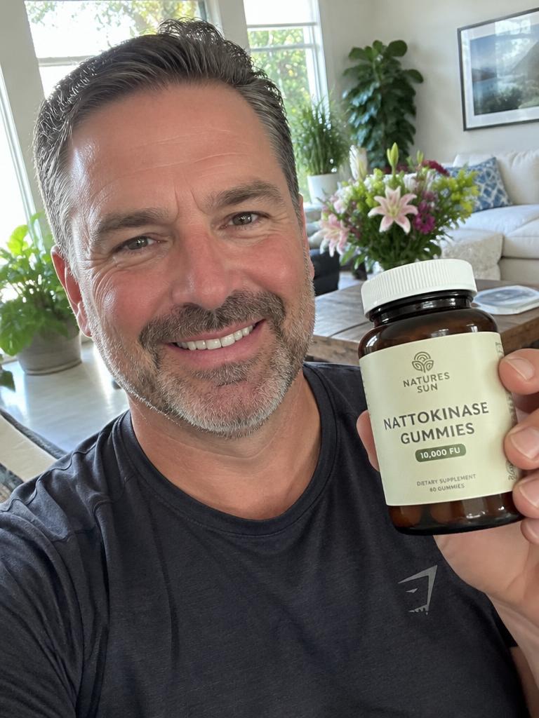 Smiling customer holding a jar of Nattokinase gummies